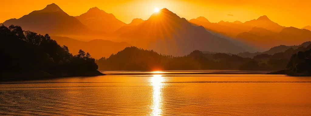 a breathtaking sunset casts a warm golden hue over a serene lake, with silhouettes of majestic mountains rising dramatically in the background.