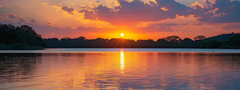 a breathtaking sunset over a tranquil lake, with vibrant hues of orange and pink reflecting on the glassy water, framed by silhouette mountains in the background.