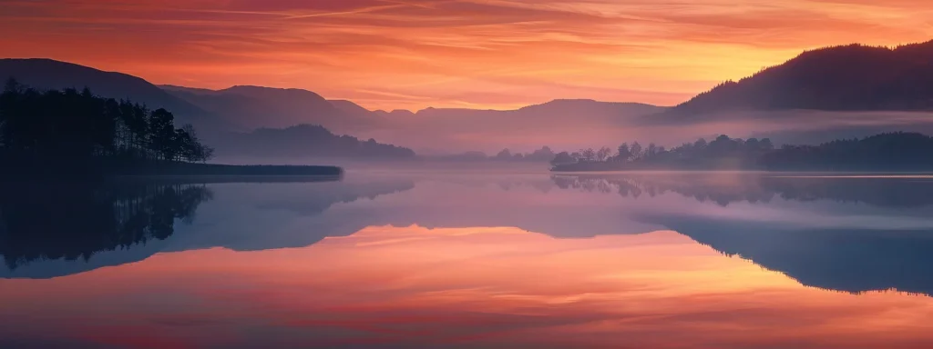 a tranquil sunrise over a misty lake reflects vibrant hues of orange and pink, with the silhouetted outline of distant mountains creating a serene and captivating landscape.